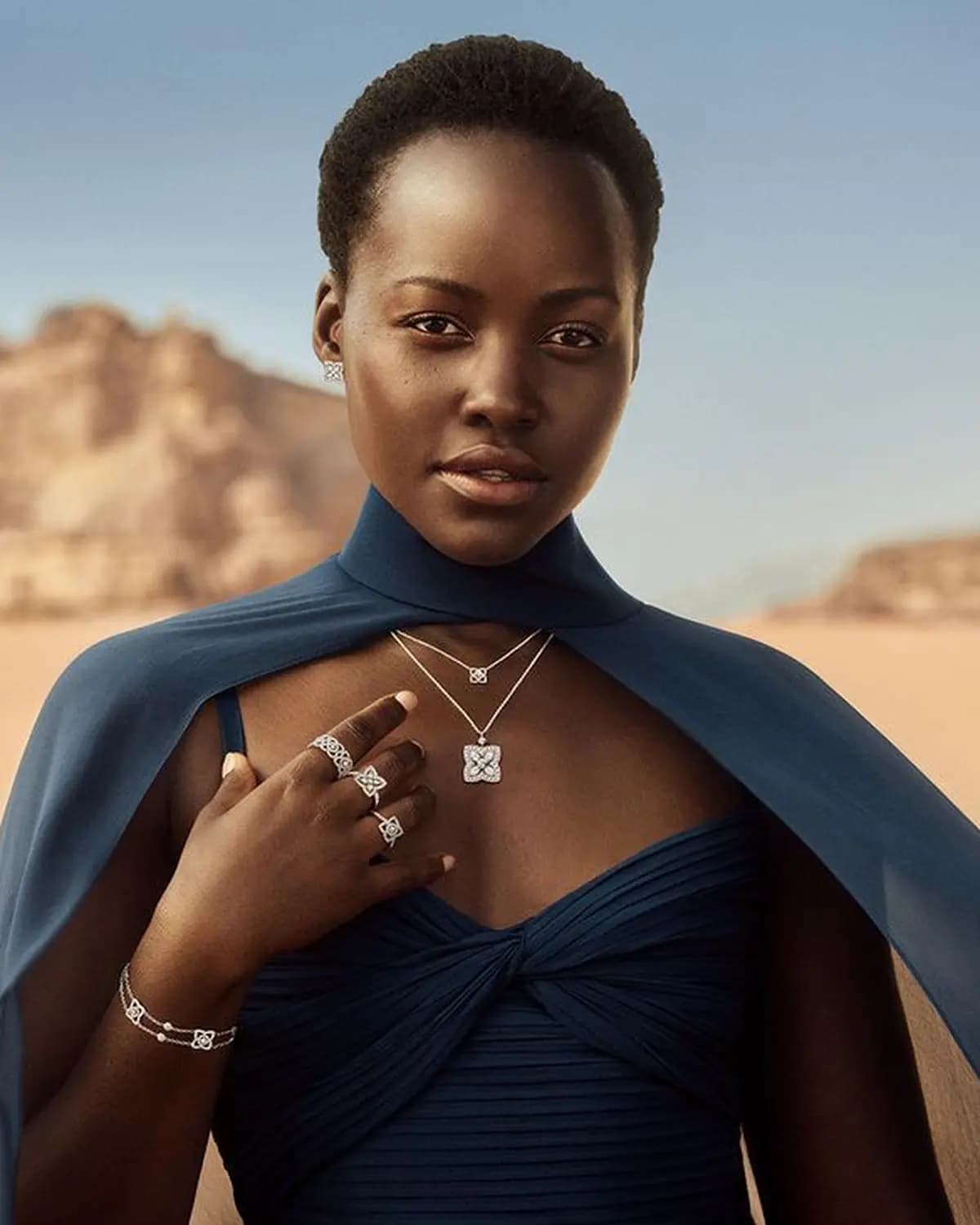 De Beers poster showing a model wearing jewellery in a desert landscape.