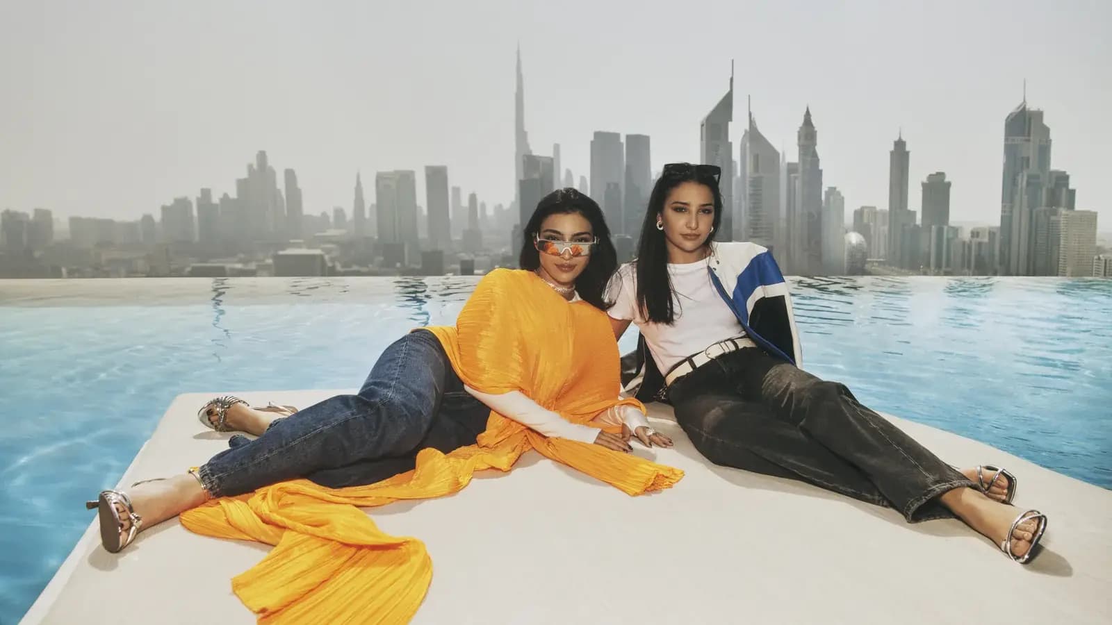 One&Only poster showing two women reclining by an infinity pool with a city skyline in the background.