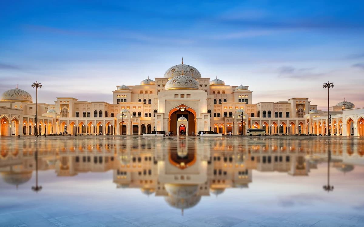 Grand domed landmark architecture in Abu Dhabi with illuminated arches, reflecting courtyard, and evening sky.
