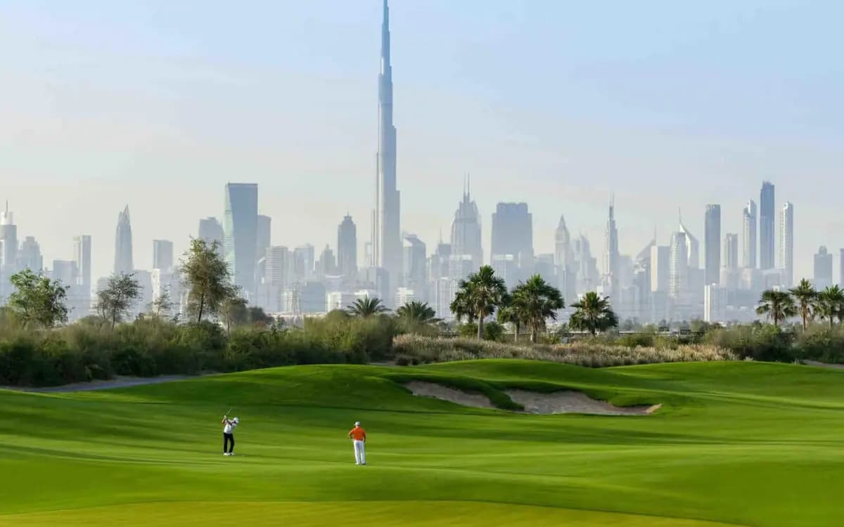 Dubai skyline with Burj Khalifa behind green golf course, palm trees, and landscaped luxury setting.