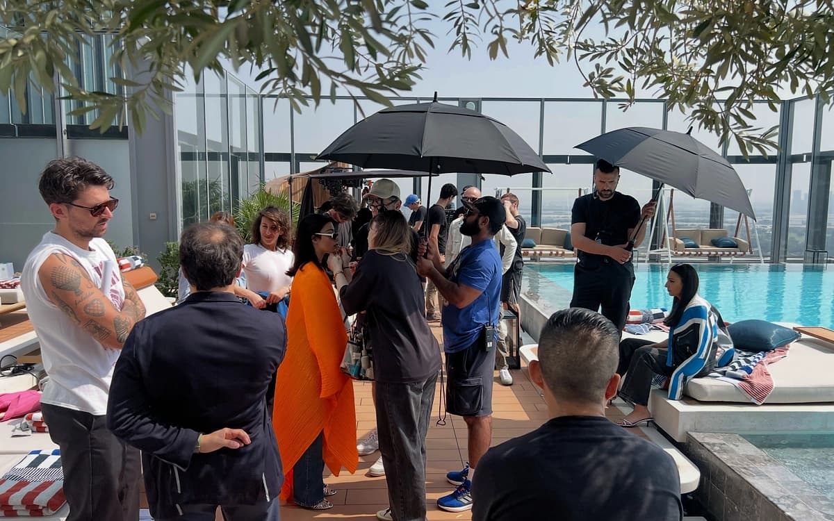Poolside production setup in the UAE with crew, talent, umbrellas, styling support, and high-rise exterior setting.