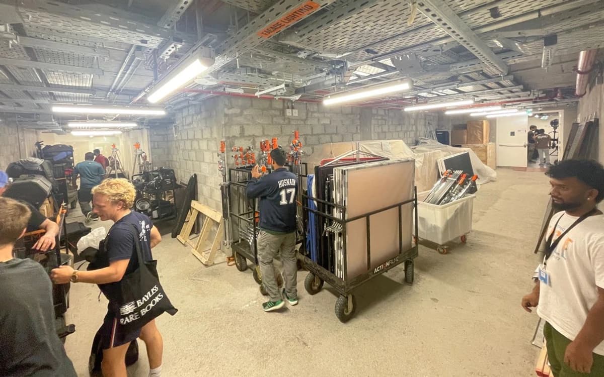 Camera and grip equipment staging area in the UAE with crew, carts, stands, frames, cases, and technical production gear.