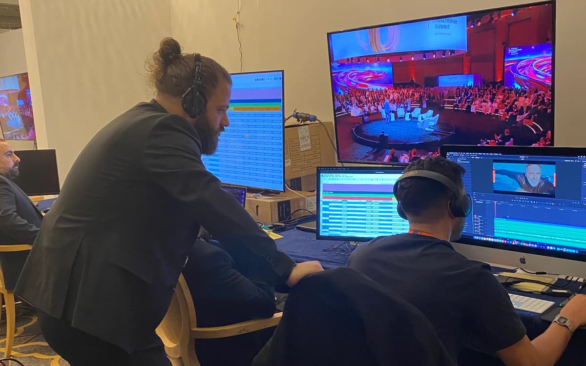 Live event content workspace in the UAE with crew, headsets, edit stations, monitors, and conference coverage screens.