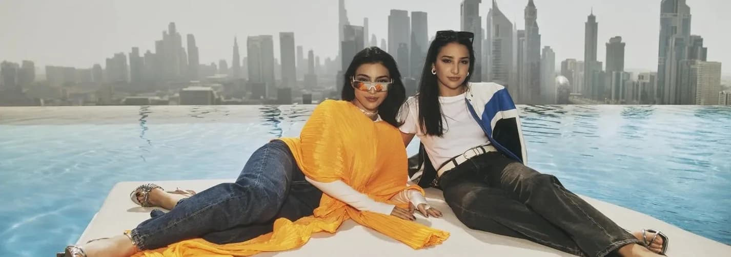 Two lifestyle talent seated beside a rooftop infinity pool in Dubai with the city skyline behind them.