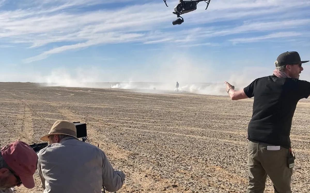 Drone filming setup on a desert location in Jordan with crew, dust, and aerial camera equipment during an outdoor production.