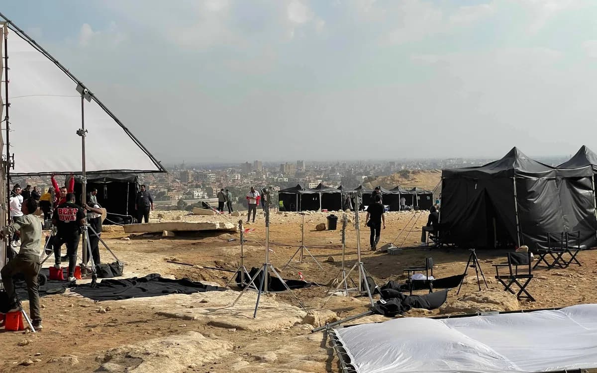 On-location production setup in Jordan with lighting stands, support tents, crew, and city backdrop during a daytime shoot.