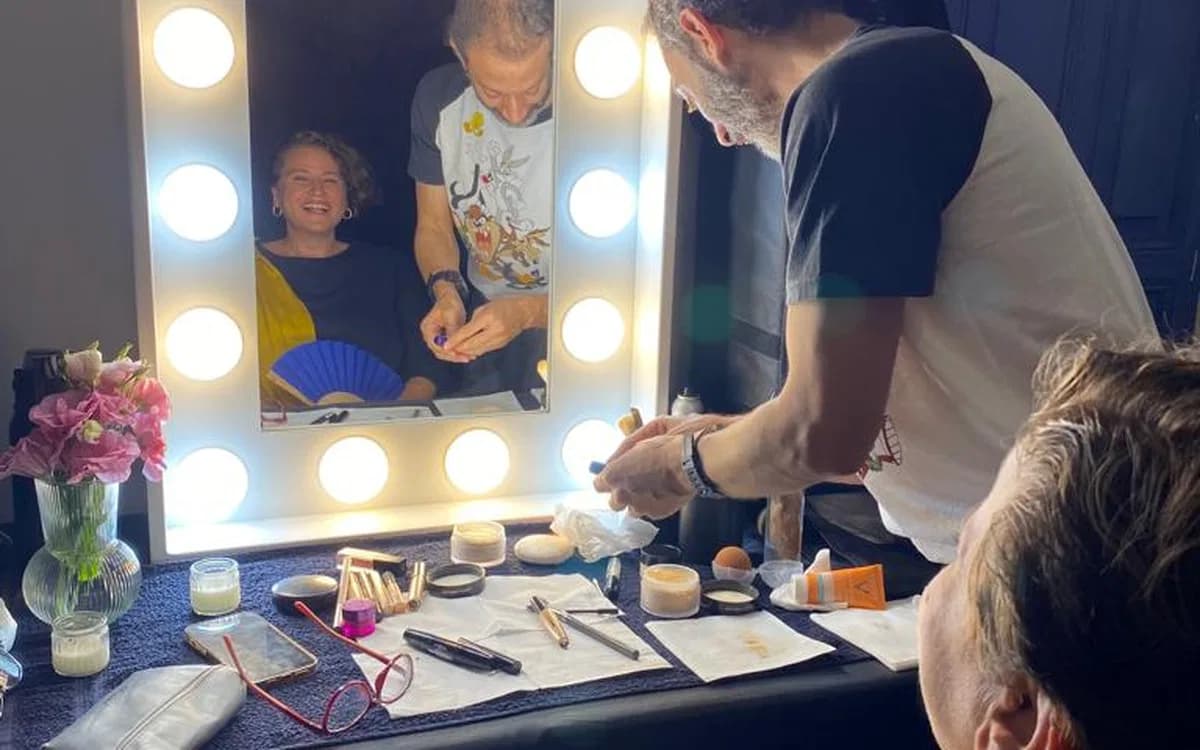 Makeup artist preparing talent at a lit mirror with beauty tools, wardrobe detail, and on-set styling support in Jordan.