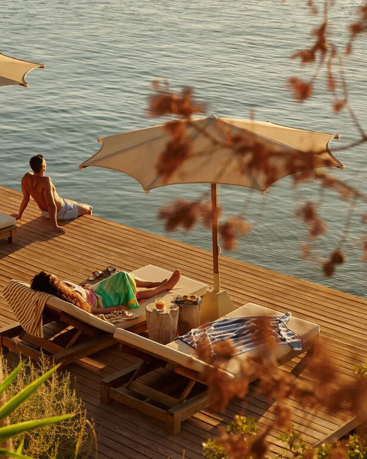 Hotels.com Gaia by the Sea poster showing guests relaxing on a seaside deck with lounge chairs and umbrellas.