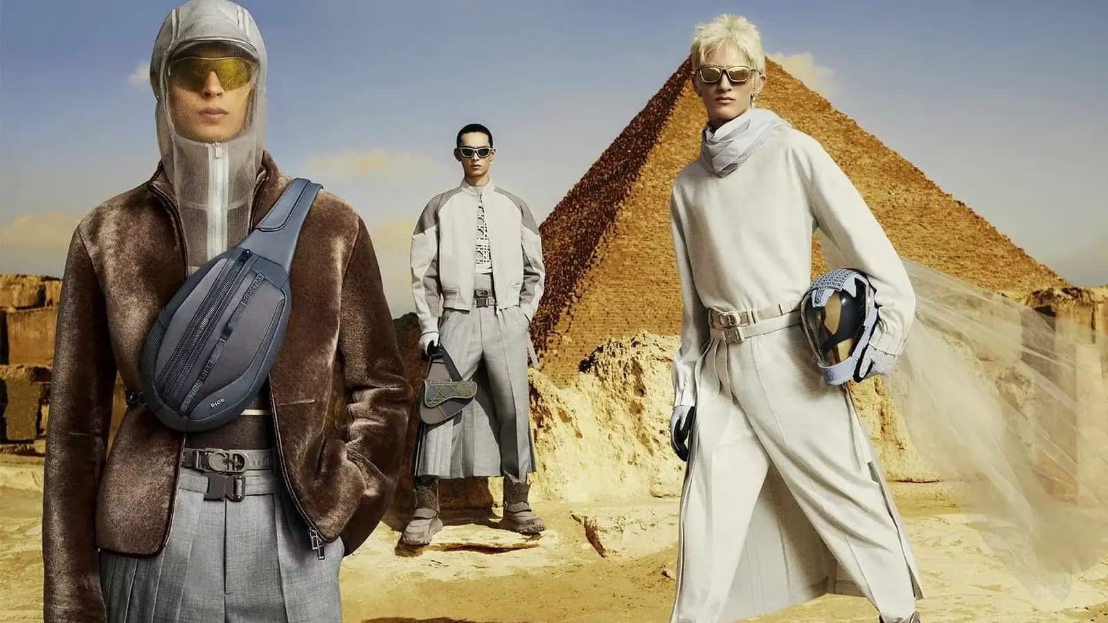 Dior Fall 2023 Men's Campaign poster showing three fashion models in desert styling with a pyramid backdrop.