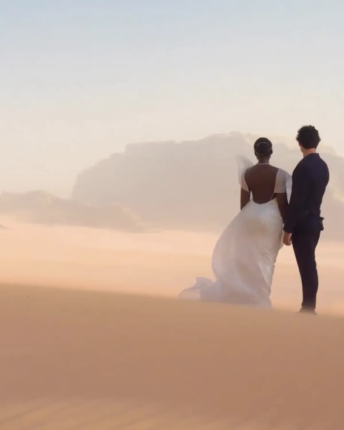 Where It Begins poster showing a bride and groom standing together in a soft desert landscape.