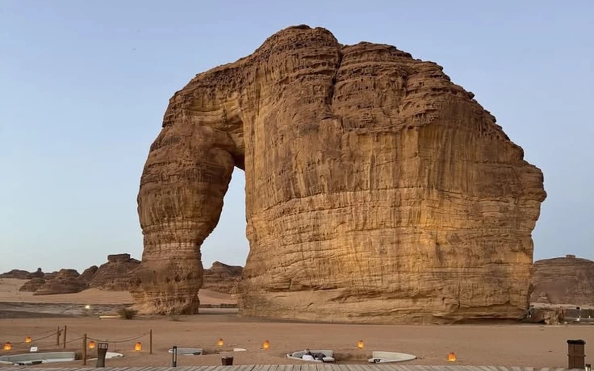Elephant Rock in AlUla, Saudi Arabia, with sandstone formation, desert seating, and warm evening light.