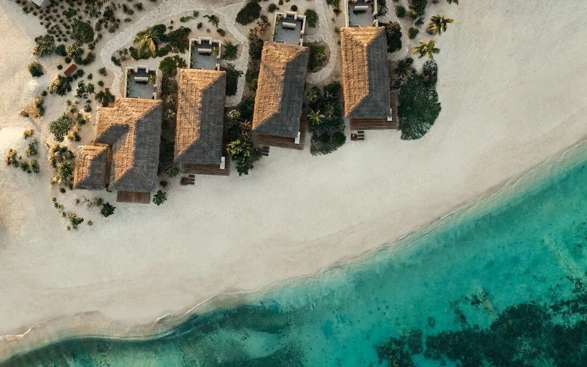 Aerial view of a Red Sea beach in Saudi Arabia with white sand, turquoise water, reef formations, and coastal villas.