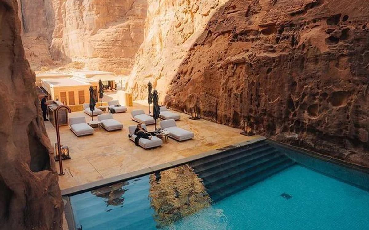 Luxury canyon resort setting in AlUla with sandstone walls, pool, lounge beds, and desert architecture.