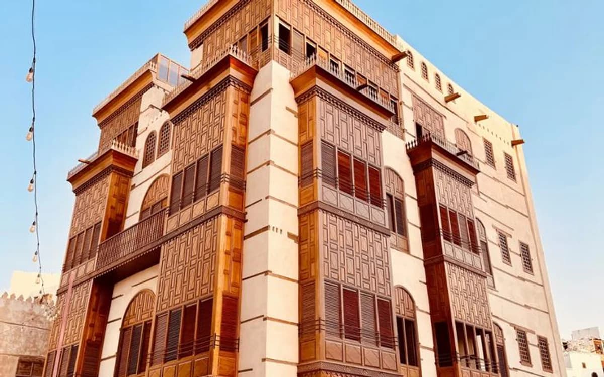 Historic Al-Balad building in Jeddah with wooden rawashin balconies, coral-stone architecture, and warm city light.