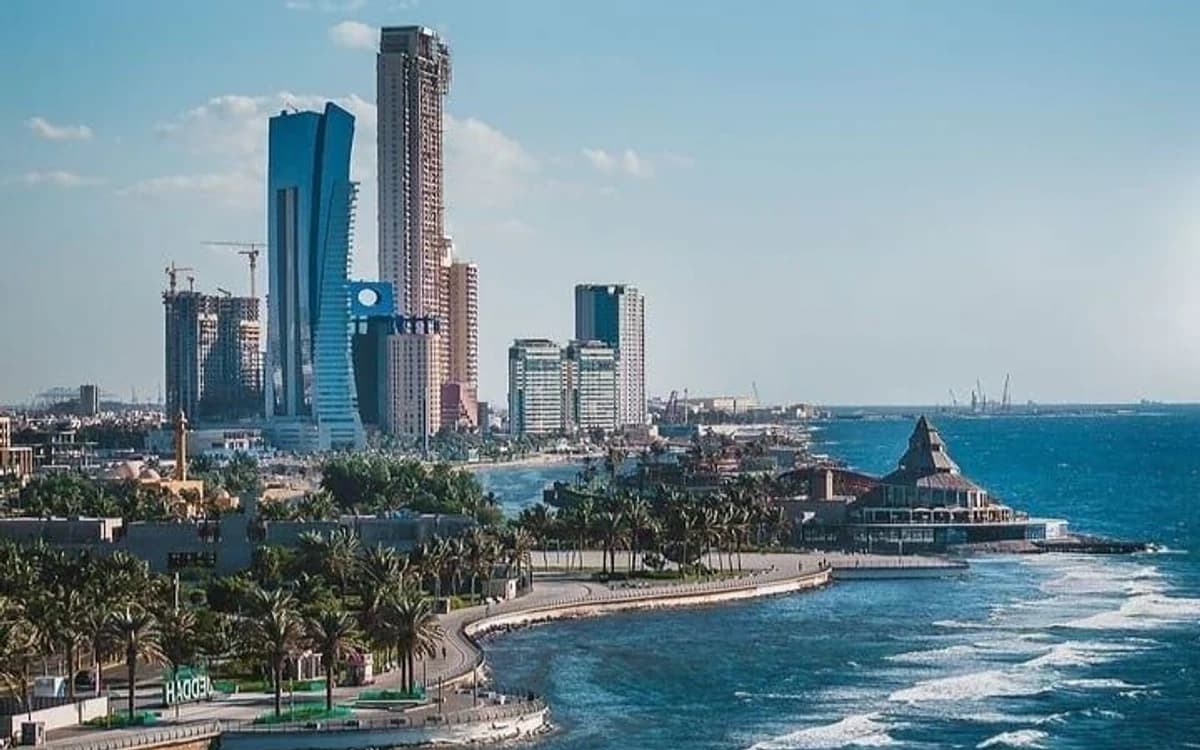 Jeddah Corniche coastline in Saudi Arabia with Red Sea waves, waterfront road, palm trees, and modern skyline.