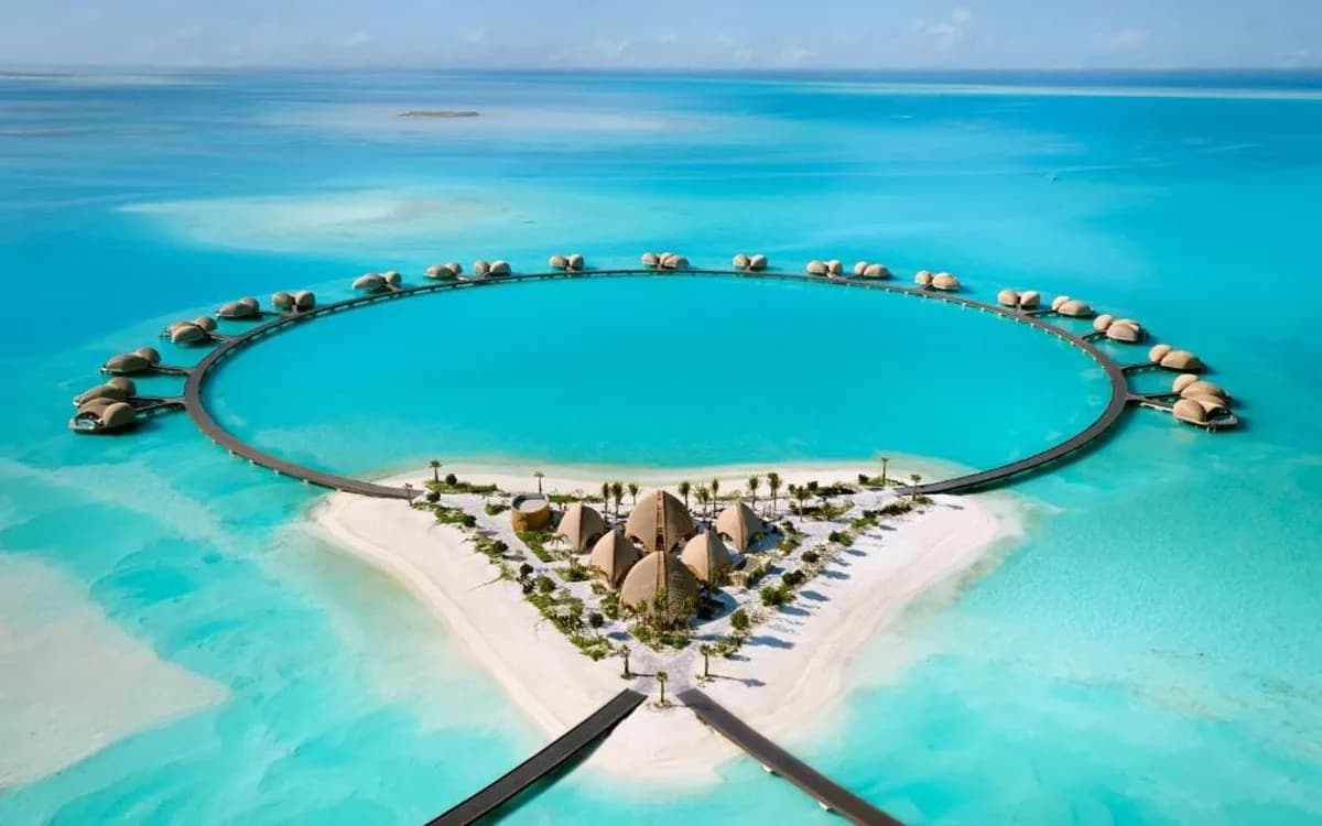 Aerial view of Shebara Resort overwater villas in the Red Sea with circular walkway, white sand, and turquoise lagoon.