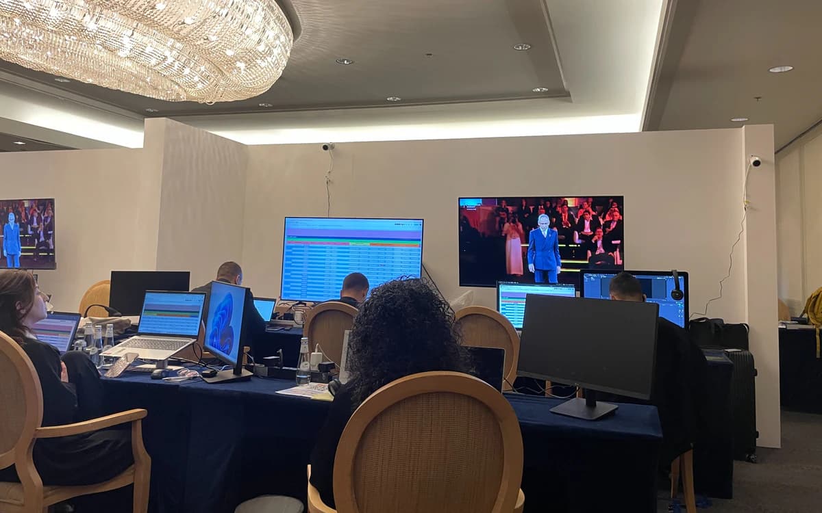 Production coordination room in Saudi Arabia with laptops, monitoring screens, schedules, and crew managing shoot logistics.