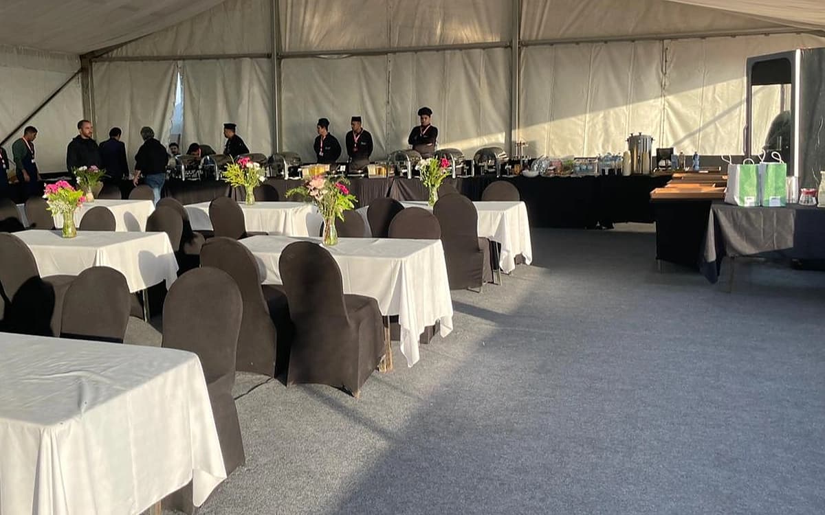 Production support tent in Saudi Arabia with catering tables, seating, crew, and service setup inside a temporary unit space.