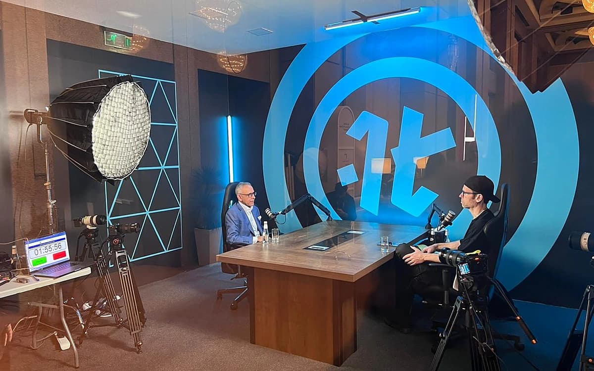 Interview filming setup in Saudi Arabia with cameras, microphones, studio lighting, and two speakers at a table.