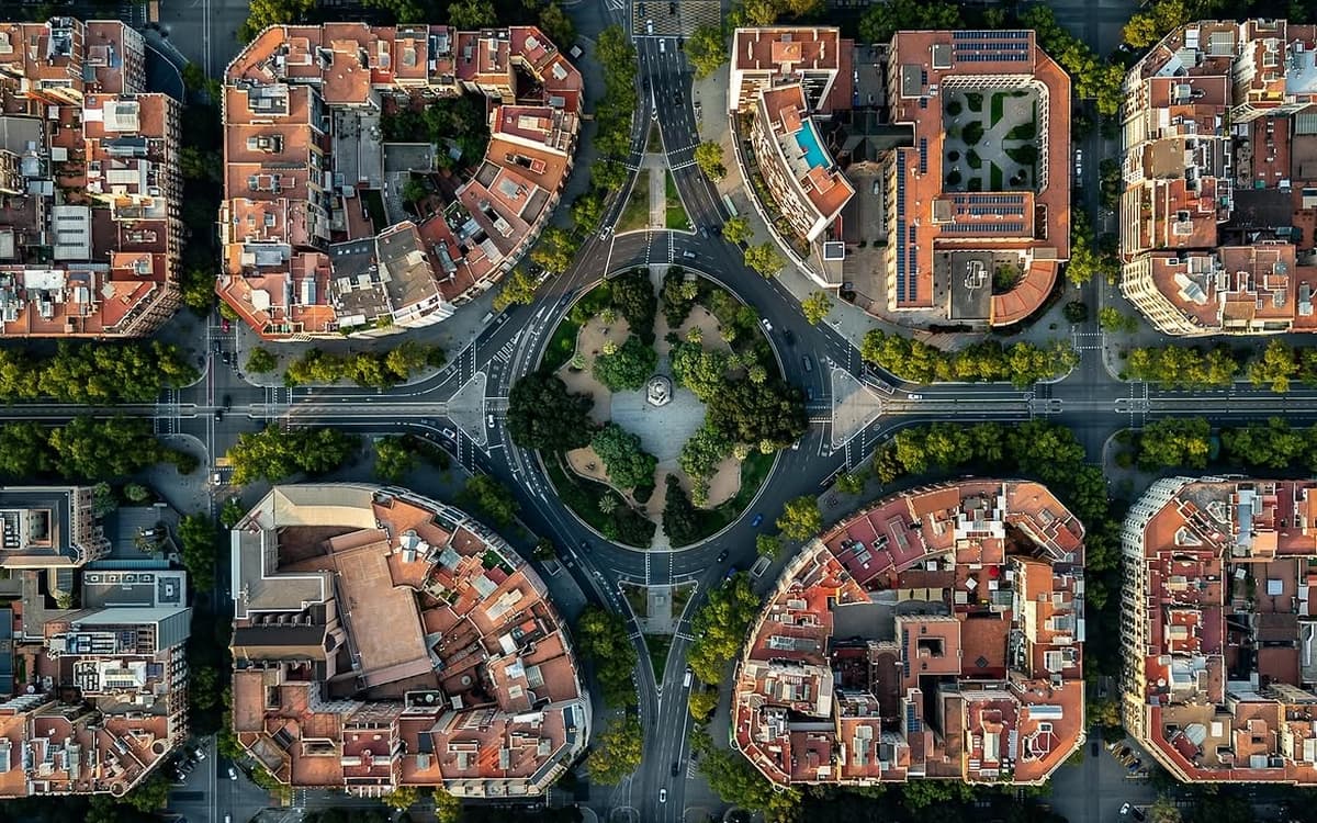 Aerial view of Barcelona's Eixample district near Plaça de Tetuan with city blocks, tree-lined streets, and traffic routes.
