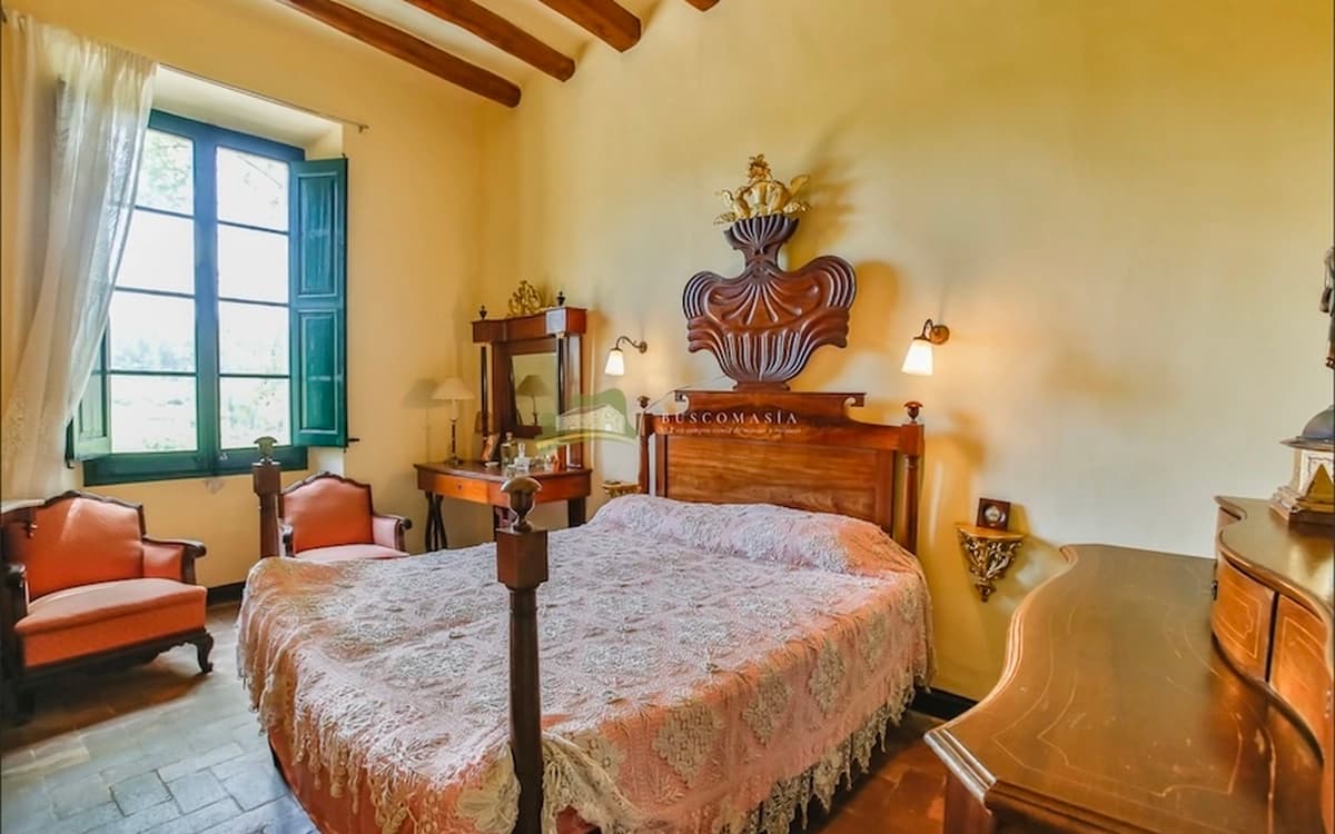 Vintage bedroom interior at Cosido Farm in Tarragona with wooden beams, antique furniture, green shutters, and warm farmhouse walls.
