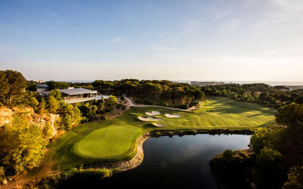 Golf course near Salou in Tarragona with green fairways, lake, clubhouse, pine trees, and coastal light.