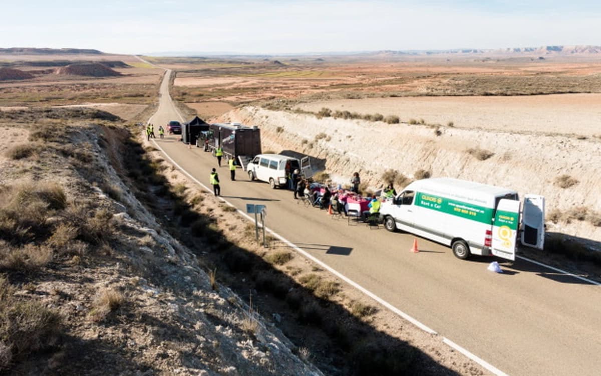 Film crew basecamp on a desert highway in Bardenas Reales with production vans, crew, road setup, and open landscape.