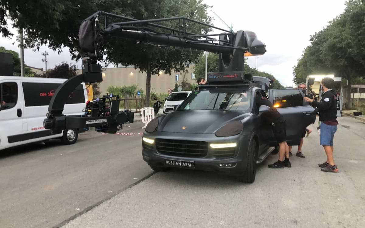 Camera tracking vehicle in Barcelona with large crane arm rig, camera system, crew, vans, and street production setup.