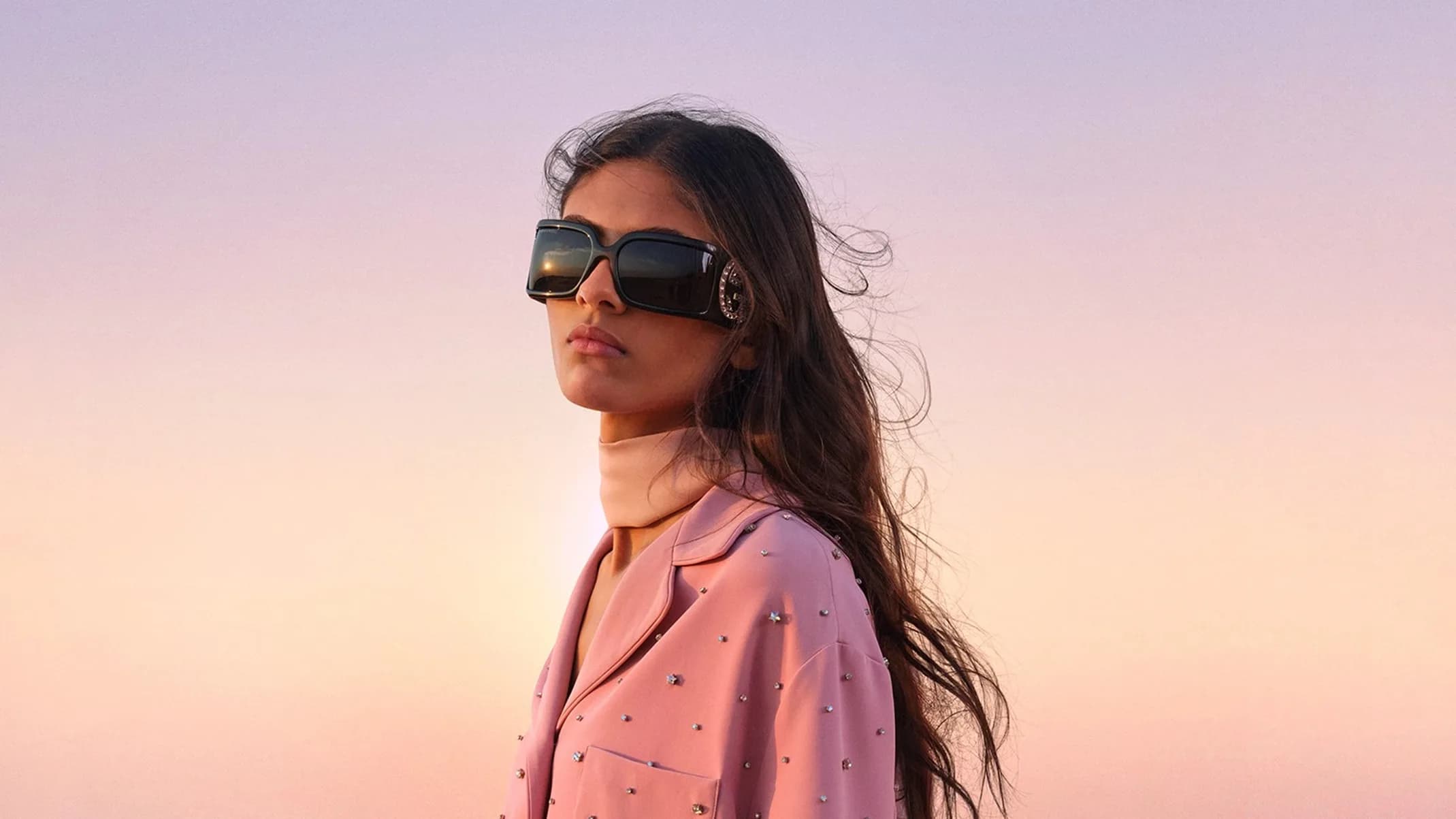 Gucci Nojum Campaign portrait of a model holding a black Gucci bag in desert dunes at sunset.