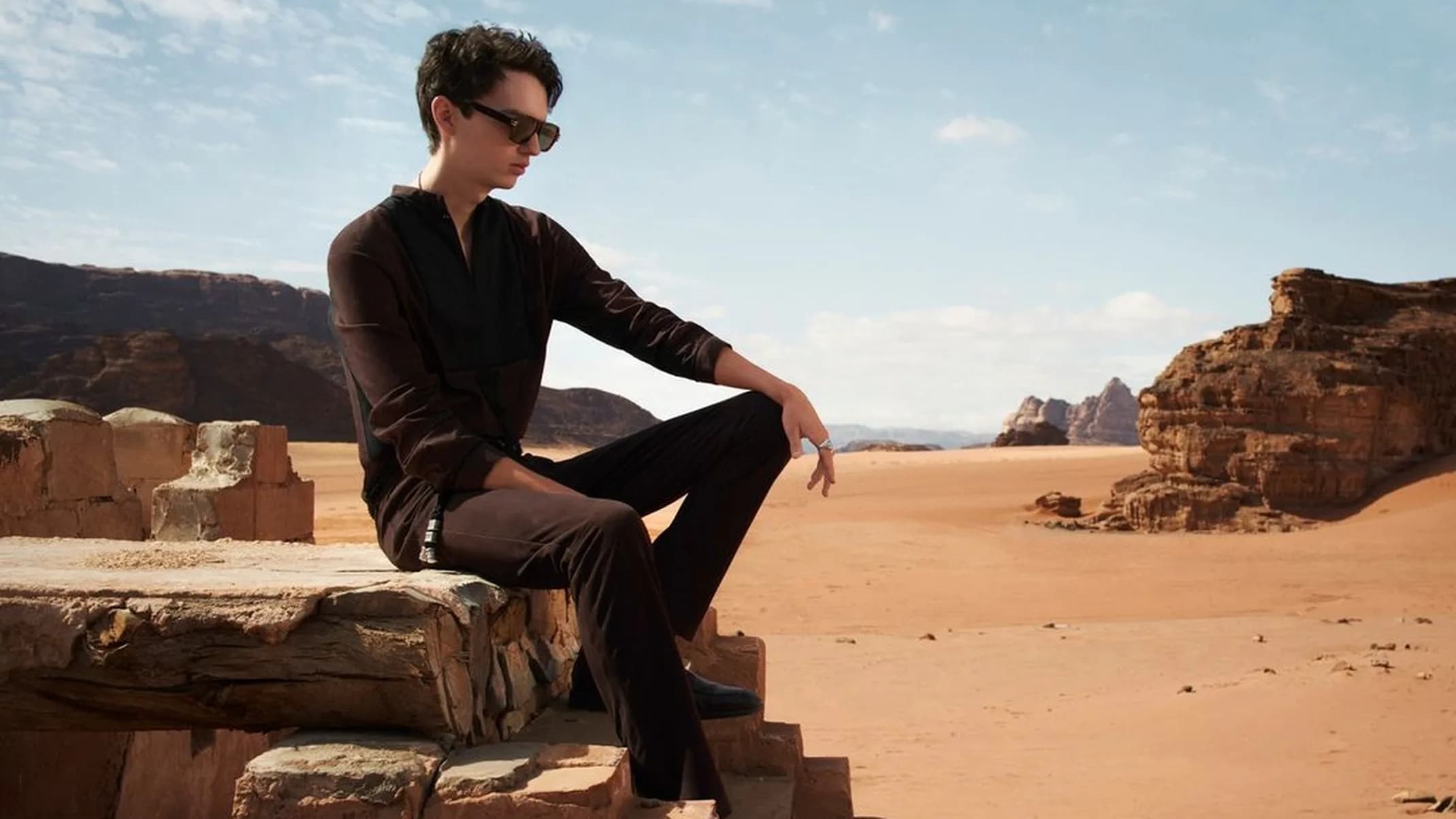 Zara Man SS22 fashion image of a model walking across a wind-shaped sand dune with rock formations in Wadi Rum, Jordan.