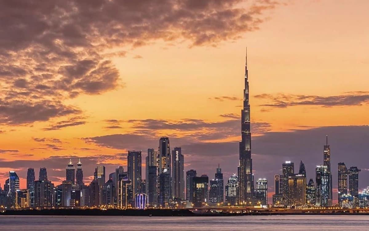 Dubai skyline at sunset with Burj Khalifa, city towers, waterfront, and warm evening sky.