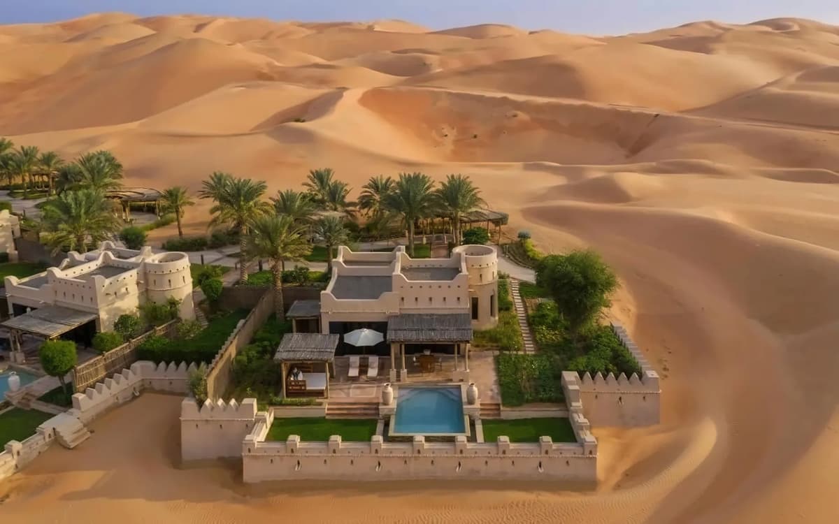 Luxury desert hospitality setting in Abu Dhabi with resort-style architecture, palm trees, private pool, and high dunes.