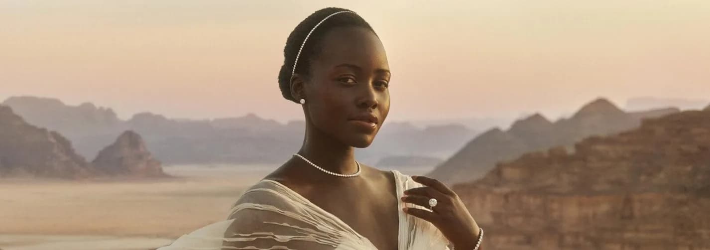 Jewellery talent in a white dress standing in the Wadi Rum desert landscape with sandstone mountains and diamond jewellery.